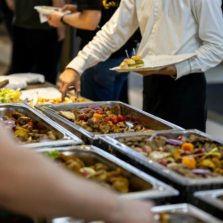 A buffet table with various dishes, including meats and salads, being served.  Hire a temporary kitchen for large events