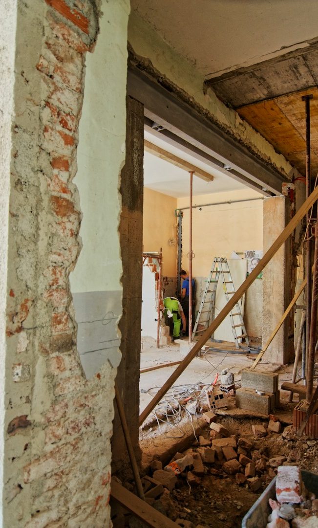 Interior of a building under renovation, showing exposed walls and construction materials.