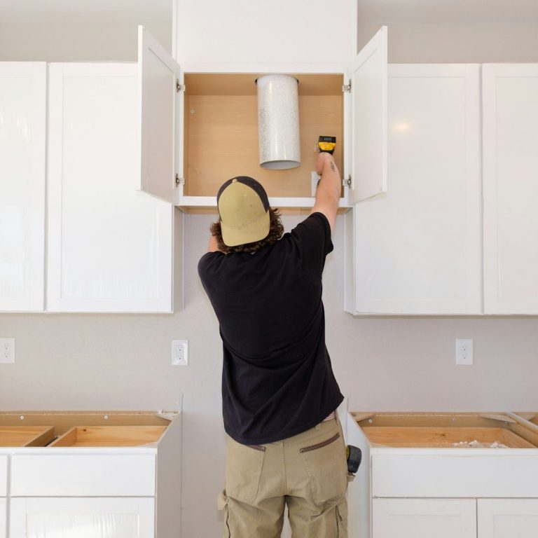 Person installing a cabinet in a modern kitchen, hire a temporary kitchen during building work