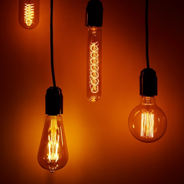 Hanging vintage light bulbs with warm orange illumination against a dark background.